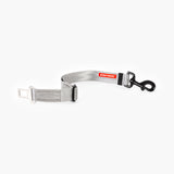 An adjustable silver dog seat belt with a 'click and go' mechanism and a red EzyDog label, designed to attach to a car's seat belt socket and a dog's harness.