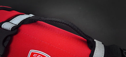 Close-up of the handle and strap on a red EzyDog harness, featuring reflective trim for visibility.